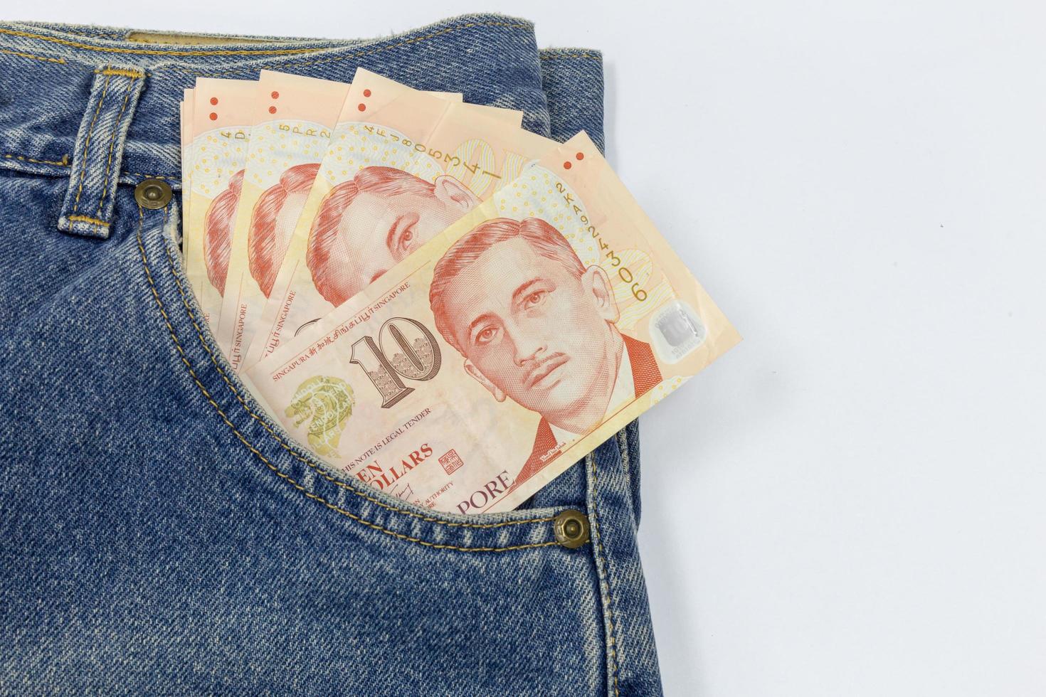 Close up Singapore dollars in a jeans pocket on white background photo