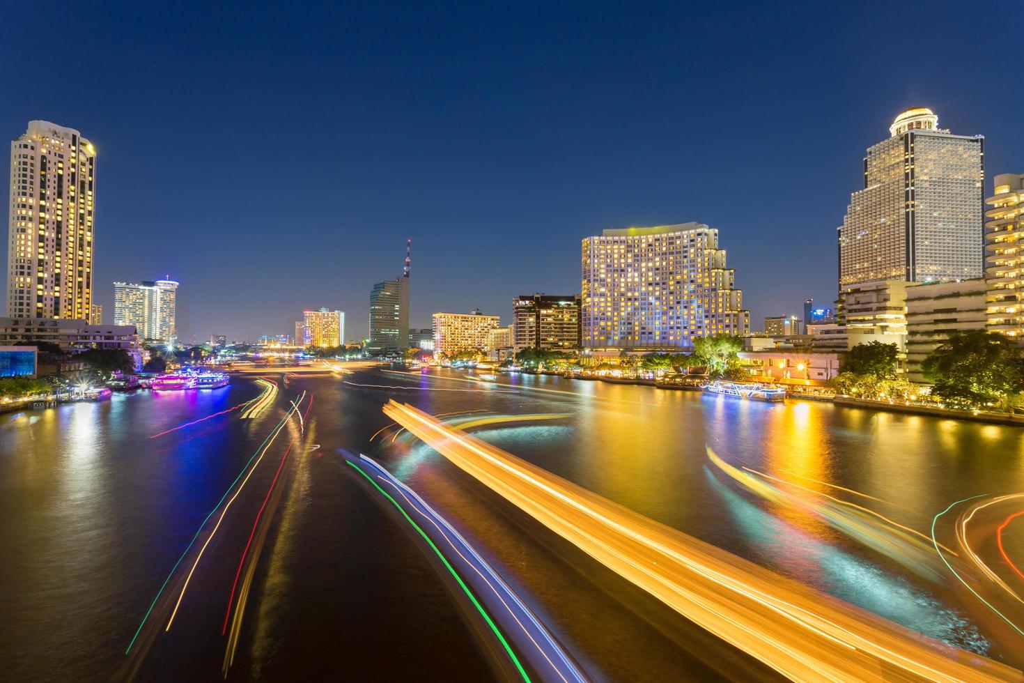 Bokeh de crepúsculo urbano abstracto y reflejo de la luz de transporte de barcos del agua en el fondo de la ciudad foto