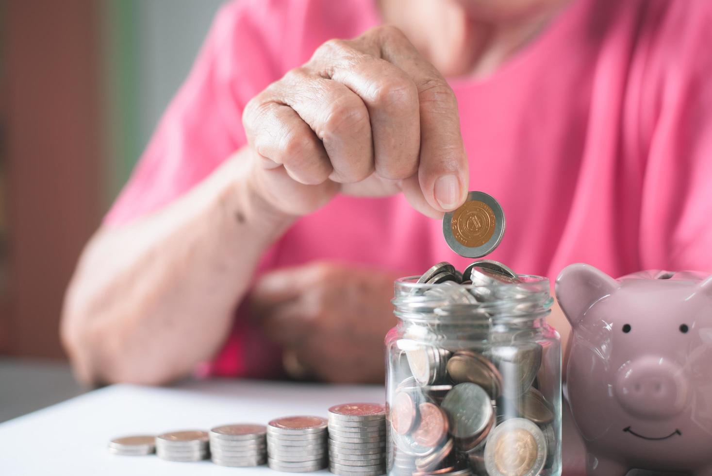 anciana sentada con monedas en un frasco de vidrio foto