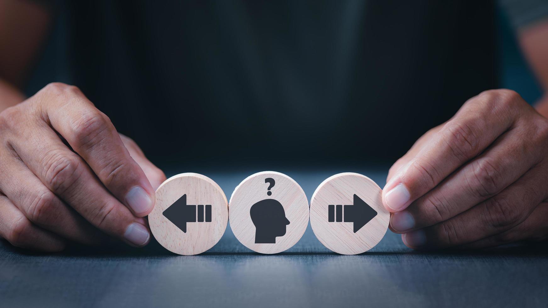 The businessman uses his hand to hold the circular wooden block lying on the table. photo