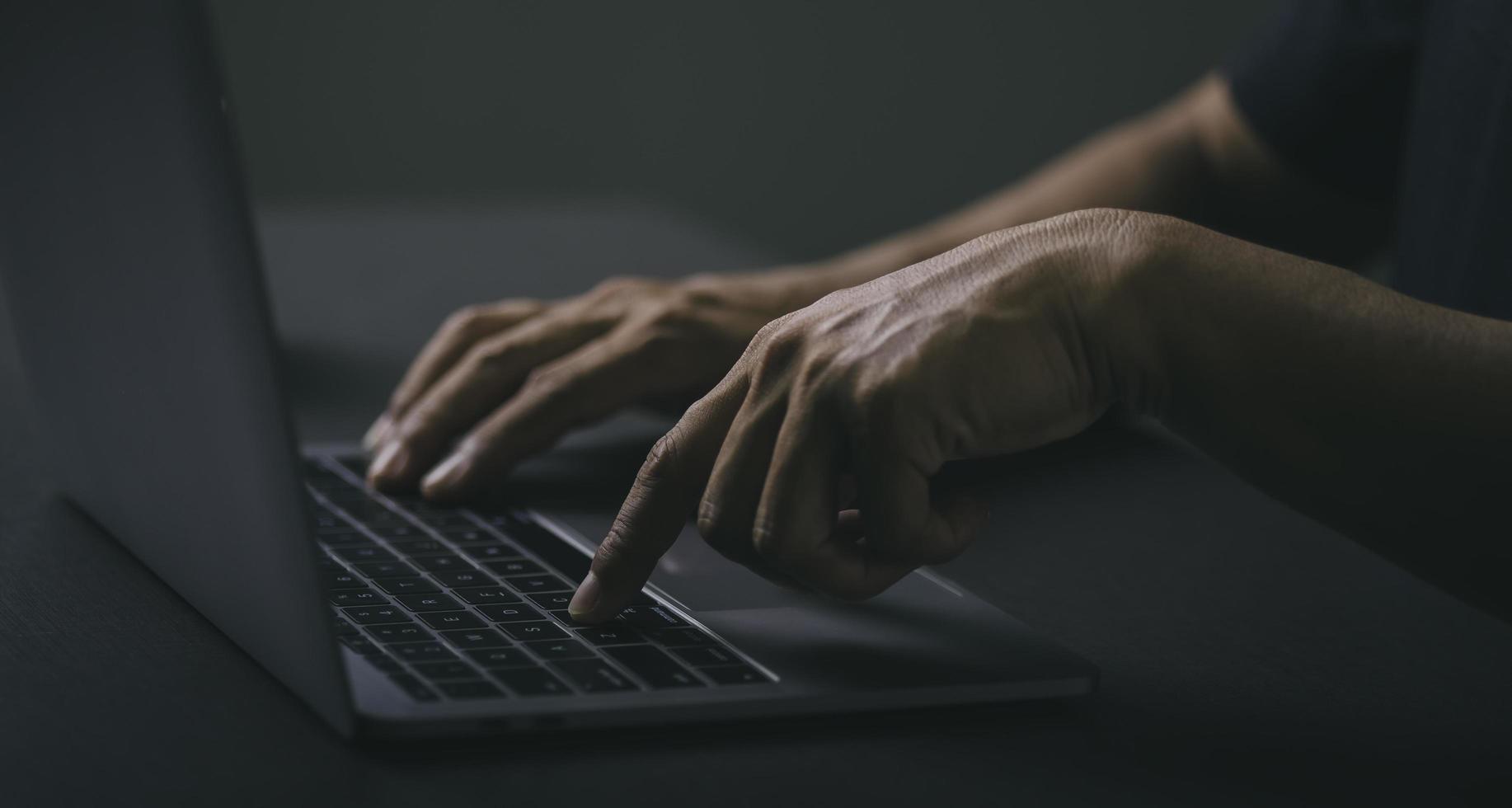 Young businessman sitting at work with his laptop on a wooden table photo