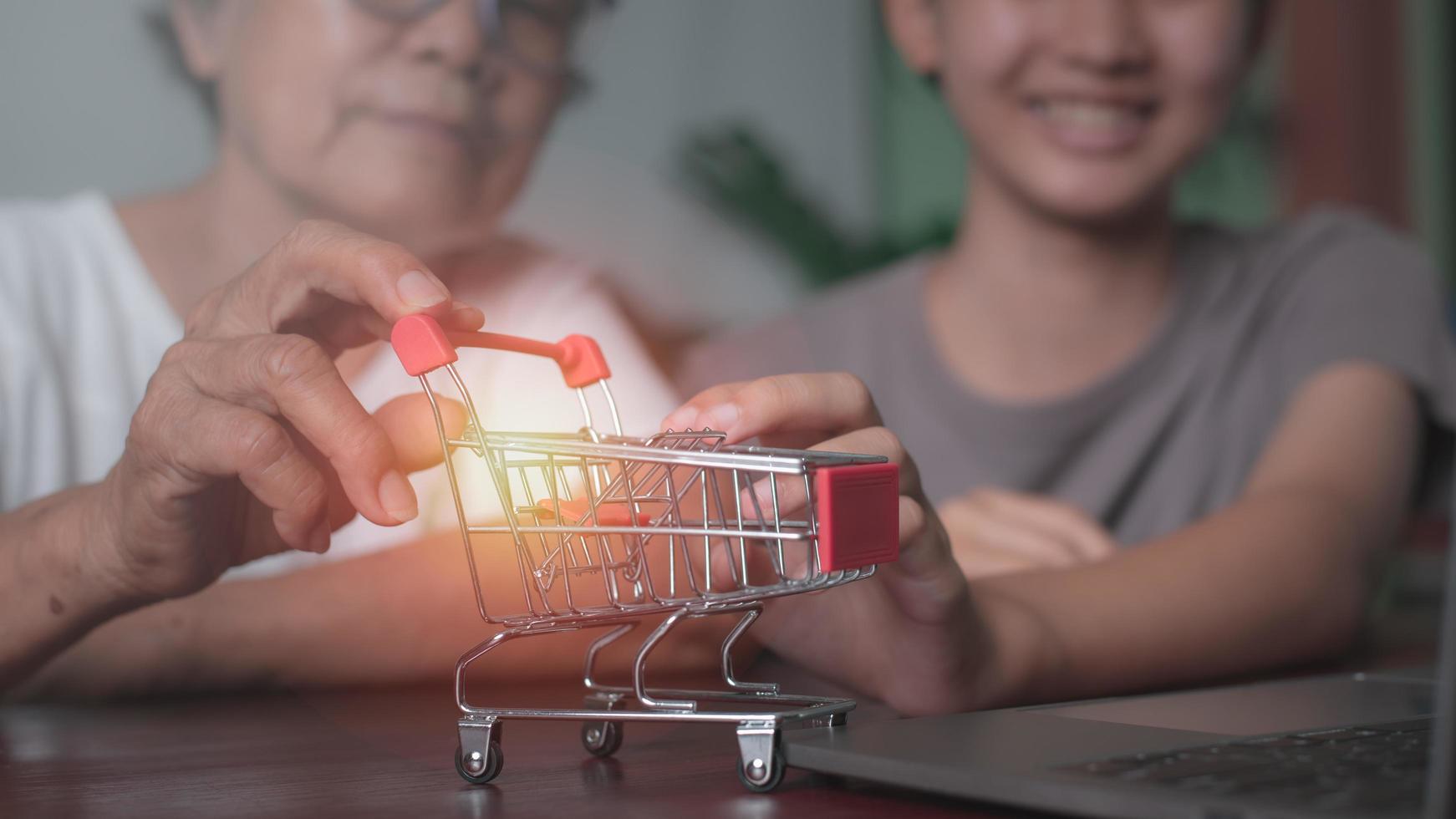 Grandma and granddaughter hold a shopping cart lying on the table, photo