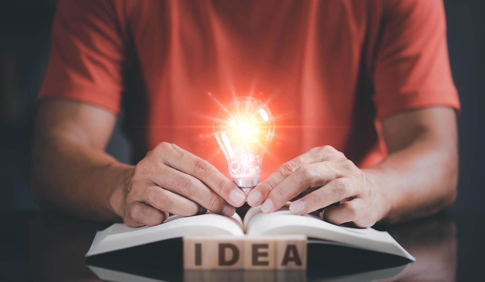 Young man holding a light bulb placed on a book photo