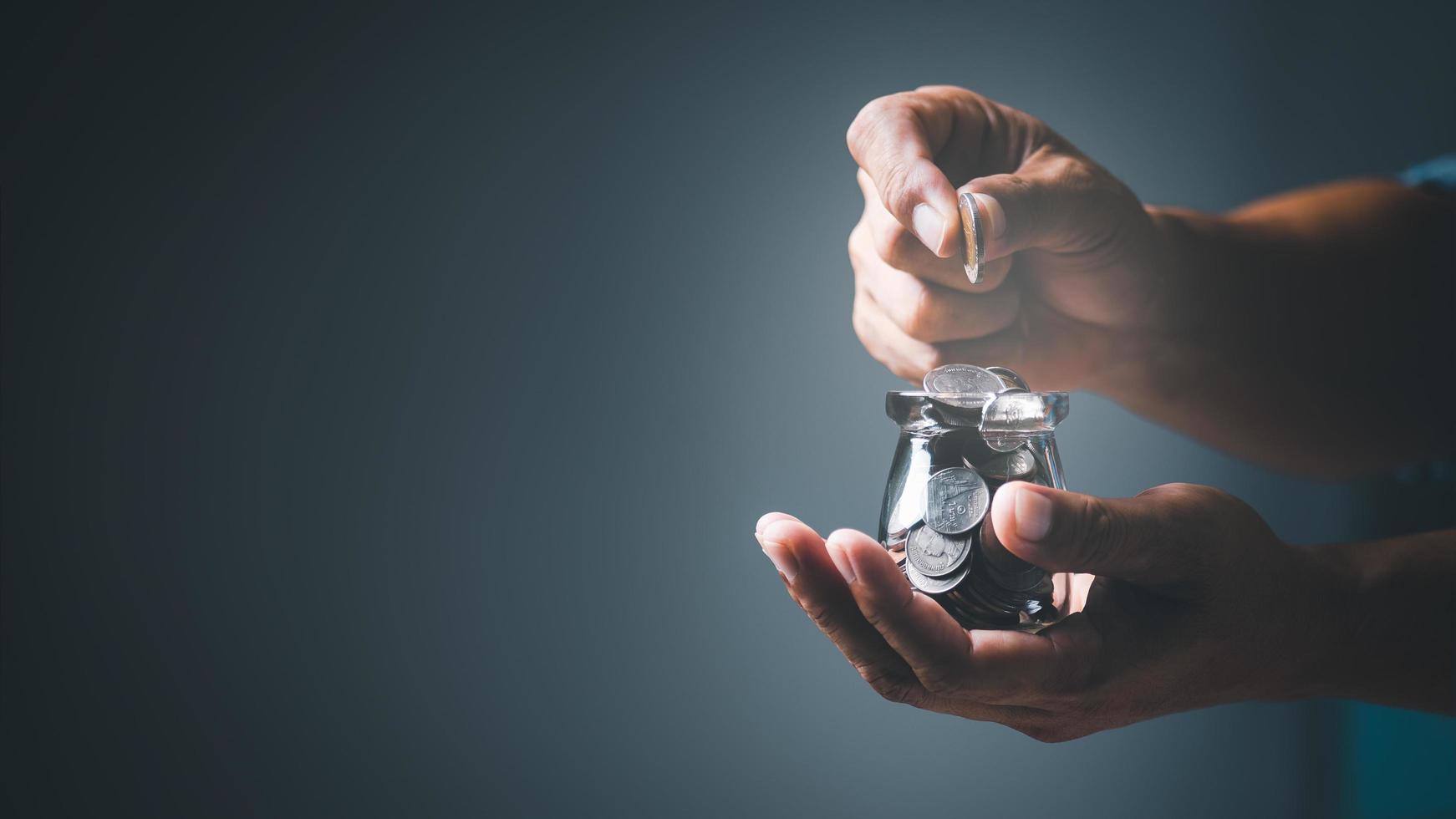 a man shows how to save and save money by putting coins in a glass jar. , to invest in finance to make profits grow and generate income through banking  and circulating cash through deposit accounts photo