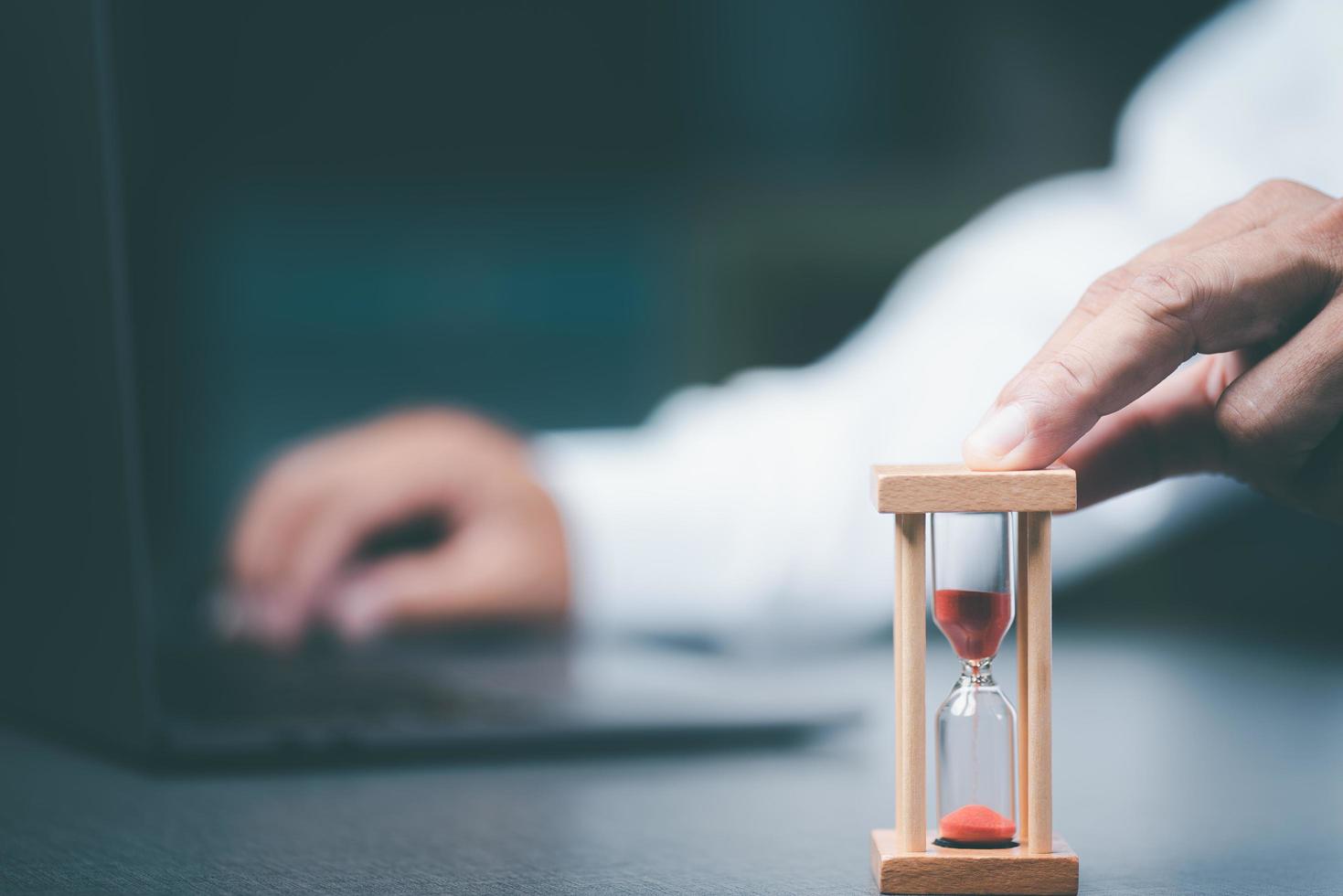 The young businessman's fingers held onto the hourglass, photo