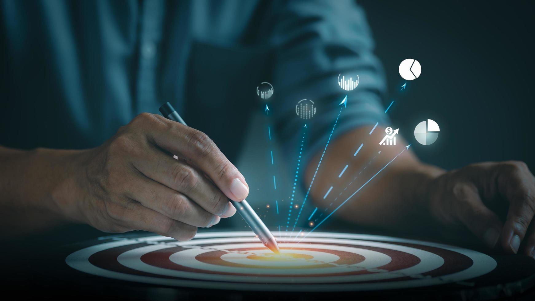 Young businessman pointing a pen at the dart board photo
