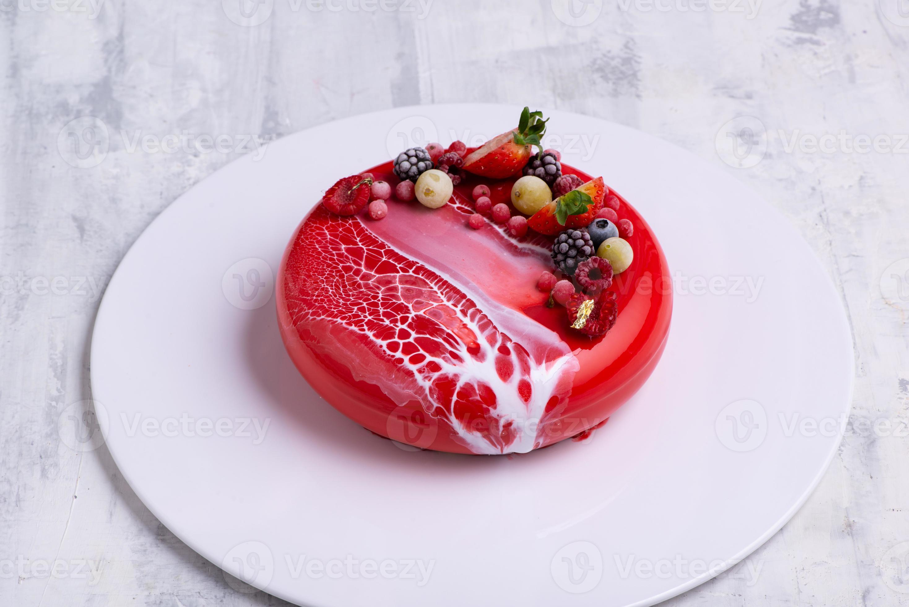 An angle shot of a mirror glaze cake decorated with berries. 9378378