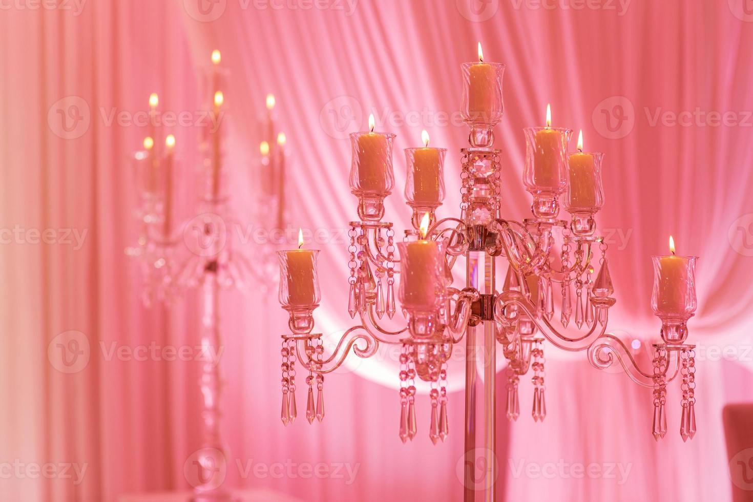 On the table is a candlestick made of crystal with candles. Decoration for holiday or celebration with pink light. selective focus photo