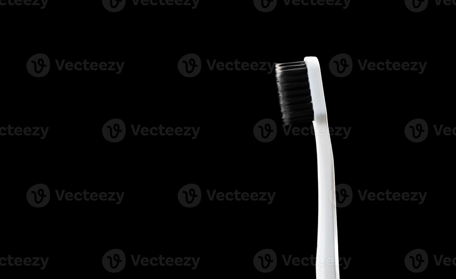 gray toothbrush with black bristles on a black background photo