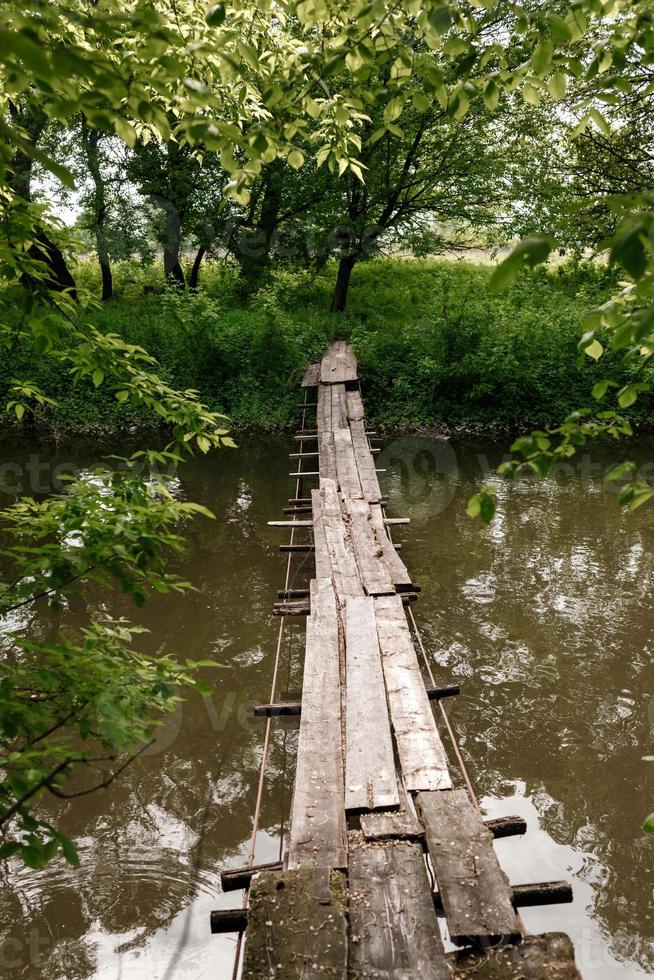 viejo puente de madera, puente de madera sobre un pequeño río, puente con la naturaleza. puente de madera sobre el río foto