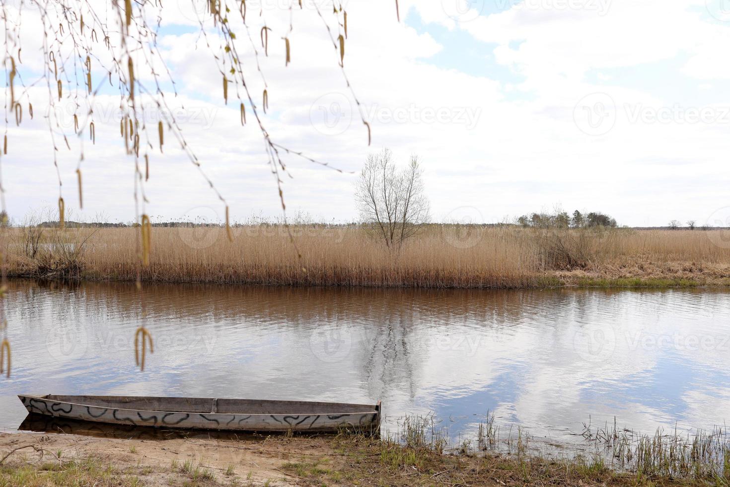 Old wooden fishing boat near the summer lake shore. photo