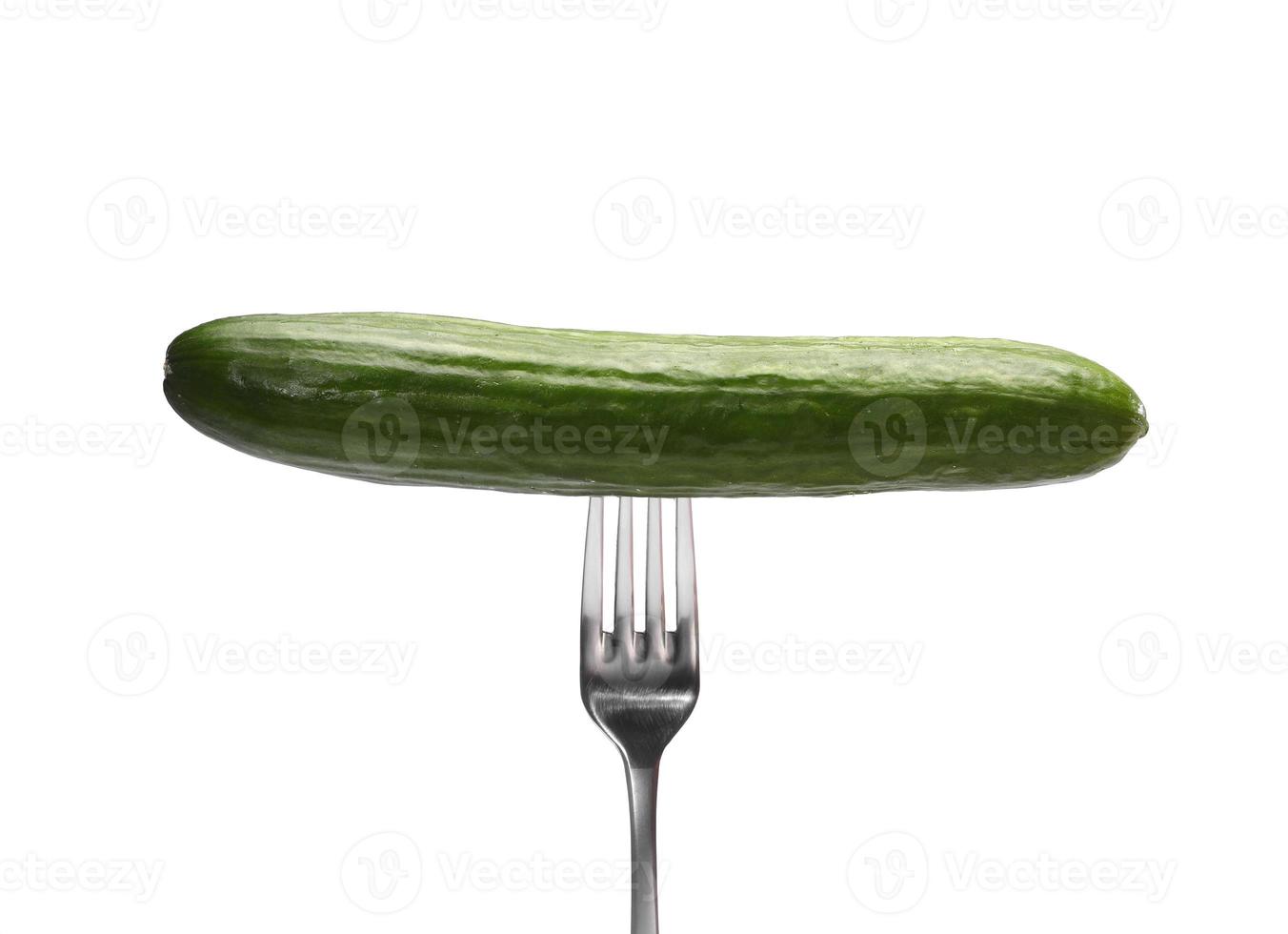 A fresh cucumber on a metal fork isolated on white background photo