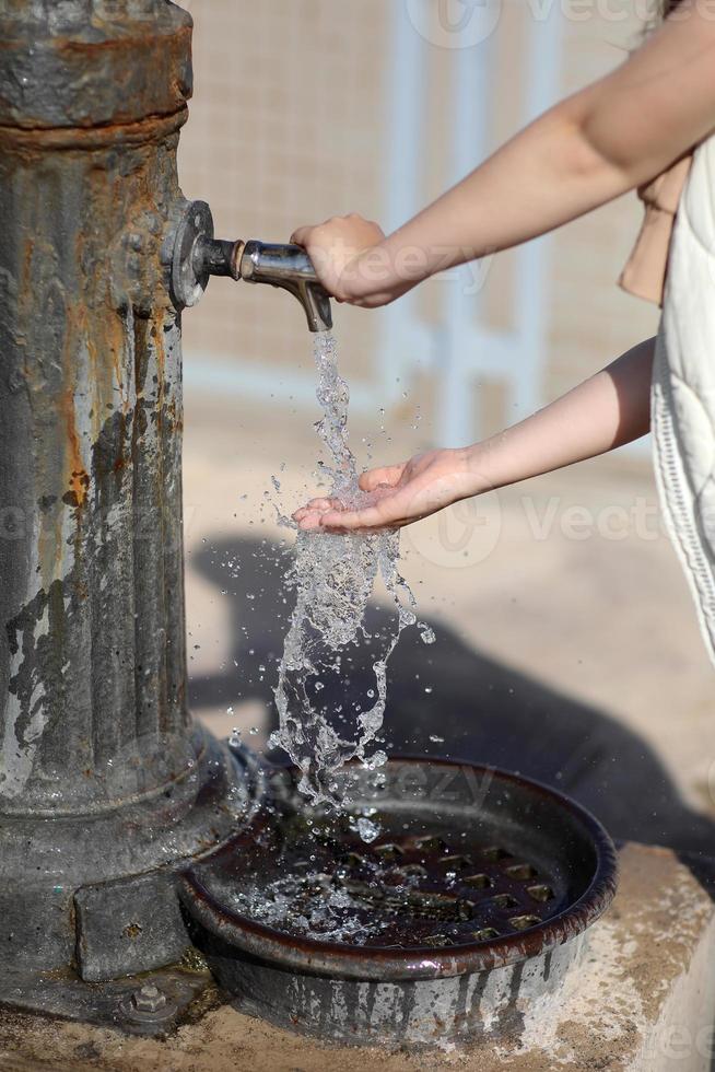 las manos del niño bajo el grifo de agua potable en la playa en un día soleado junto al mar. foto de alta calidad