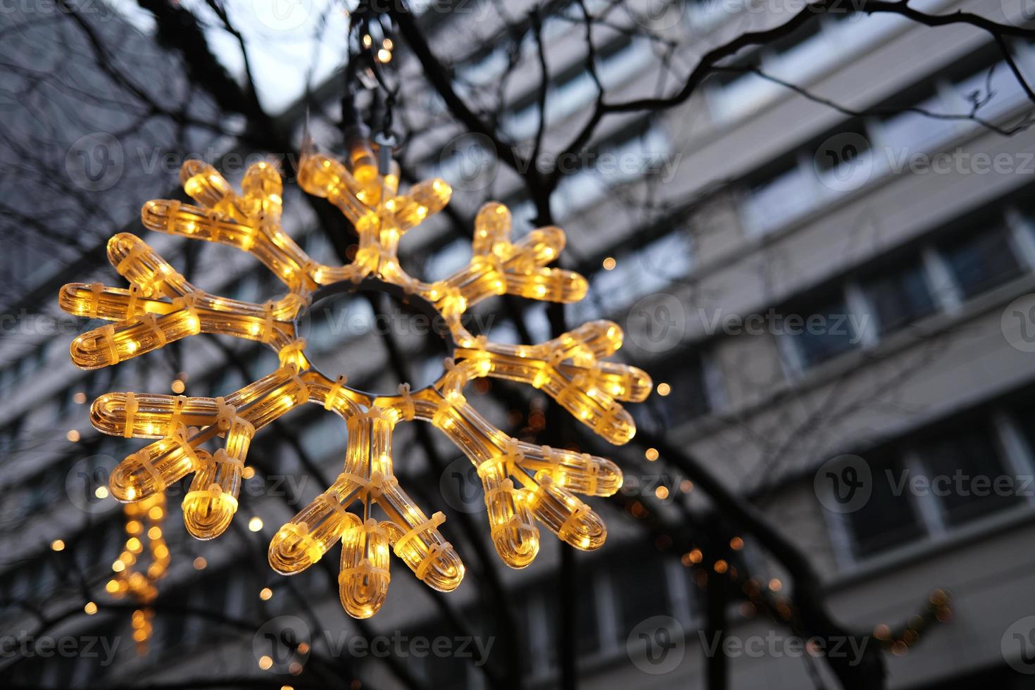 Christmas decoration hanging in front of residential building. Festive led light snowflake close up shot taken in Berlin, Germany. photo