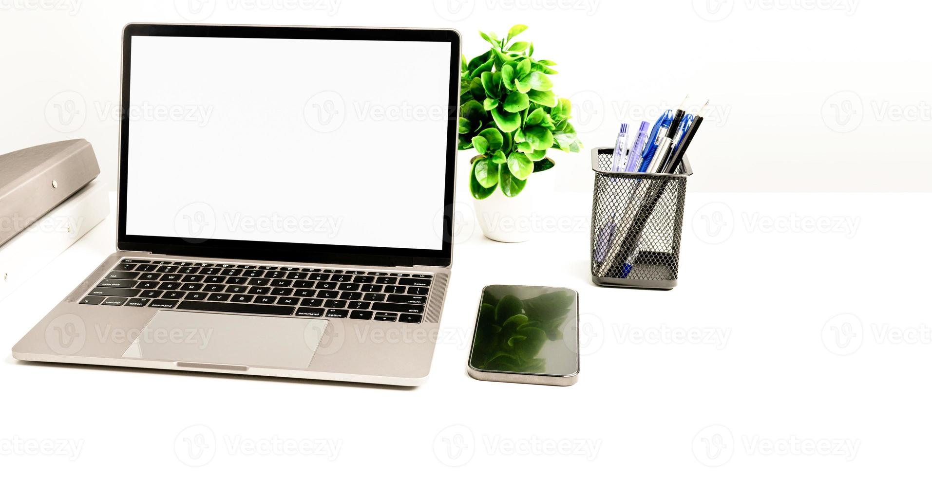 Copy space on right for design or text, Closeup, Gray, and blurred background, Blank white screen laptop on a white table in an office. Working concept using technology smartphones, notebook, internet photo