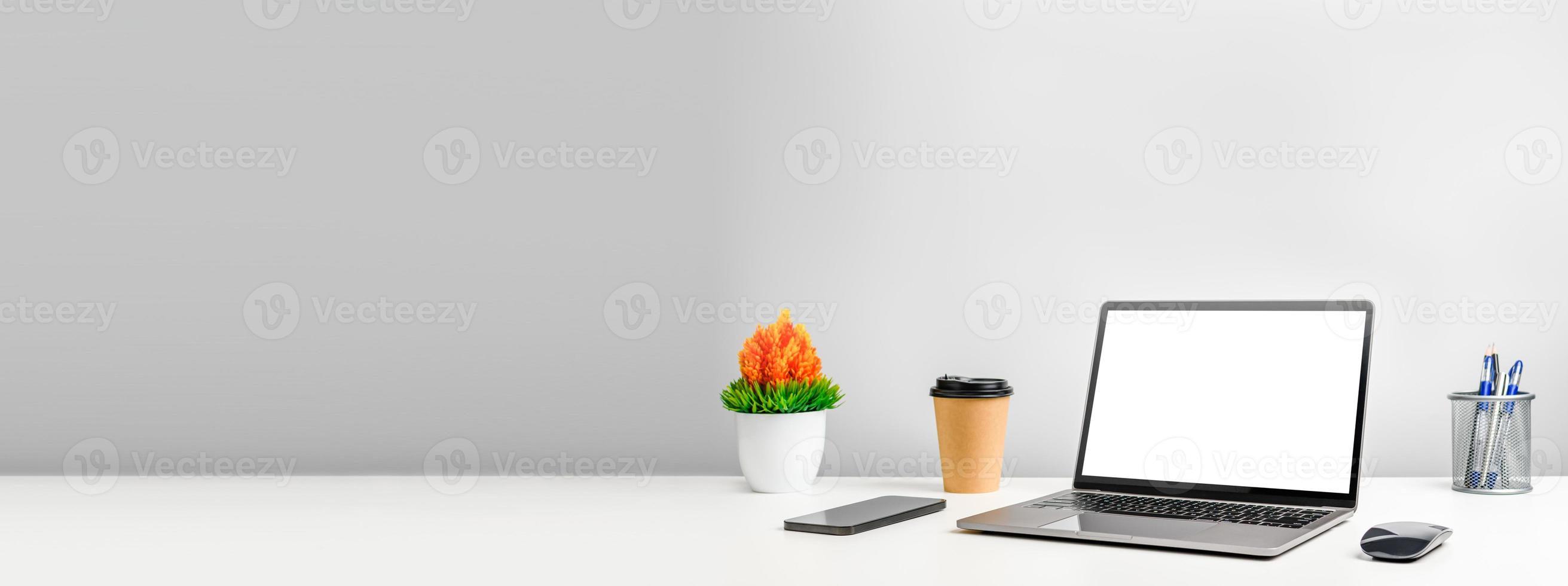 isolated, Blank white screen laptop on a white table in office. Working concept using technology smartphones, notebook, internet. Copy space on left for design, Closeup, Gray, and blurred background photo