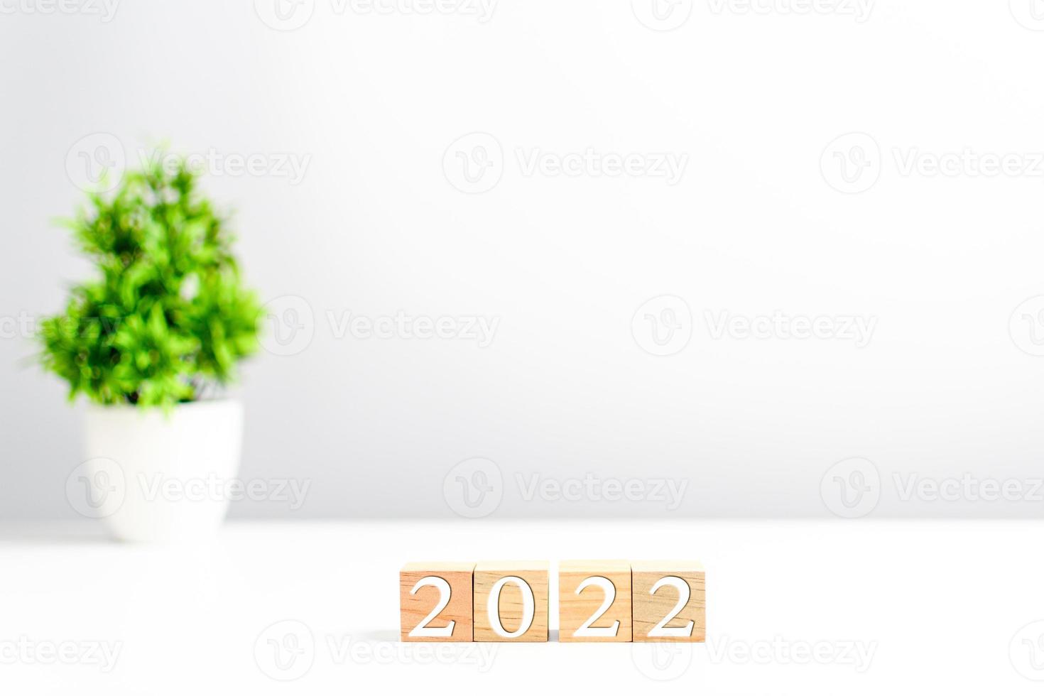 New year 2022 wood cube is on a work table. Concept of a startup that drives the economy, finance, banking, forward, future, glowing, startup, strategy, success. Copy space, Blurred, grey background photo