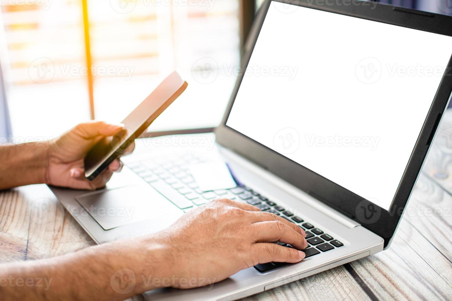 Business people use laptops blank screen with white on a wooden desk. Men use smartphones to shop online and payment. Businessmen transfer money via the Internet. Selective focus. Blurred background. photo