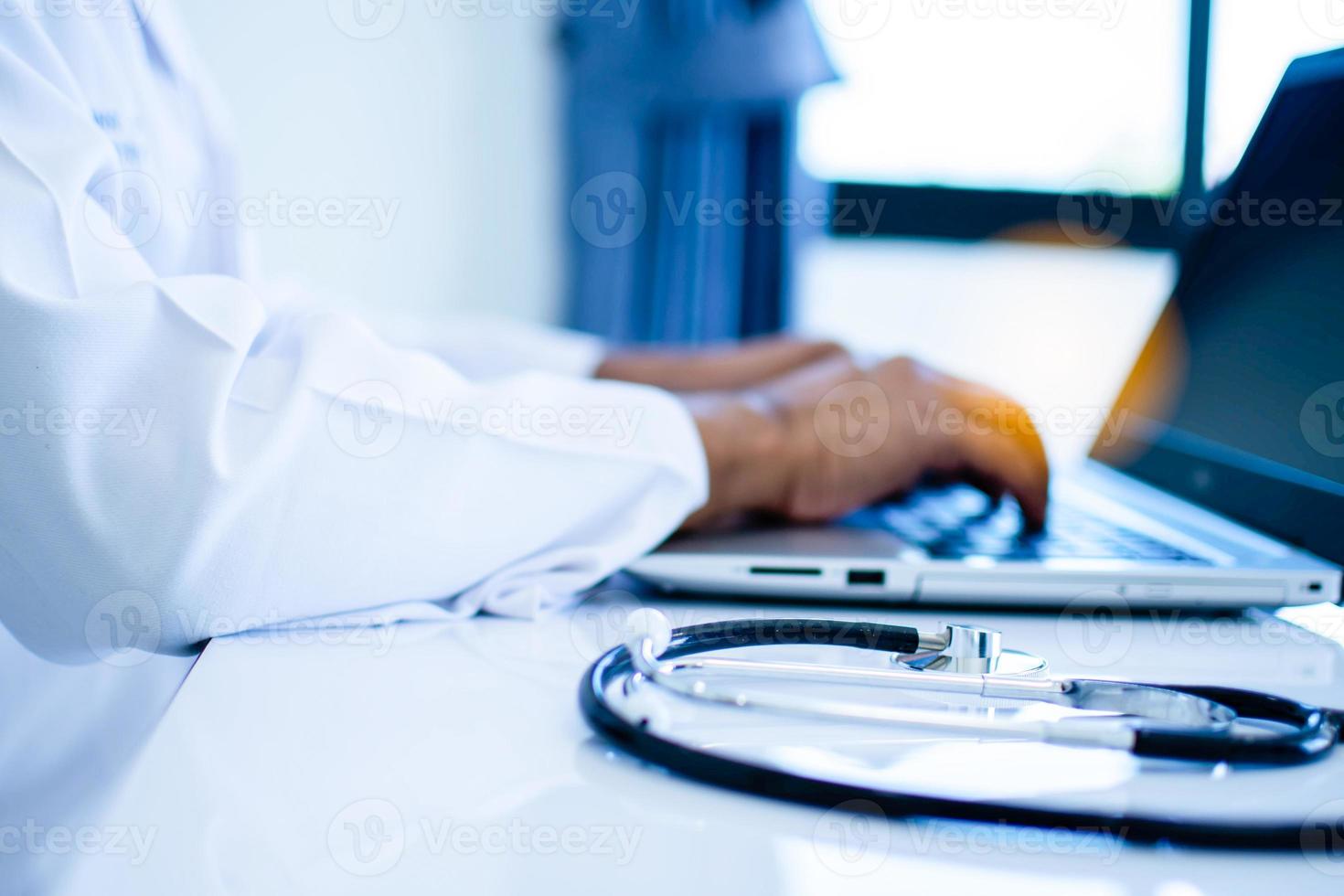 A stethoscope on a doctor's table using a laptop computer in a hospital laboratory Men do vaccine research to help people. photo