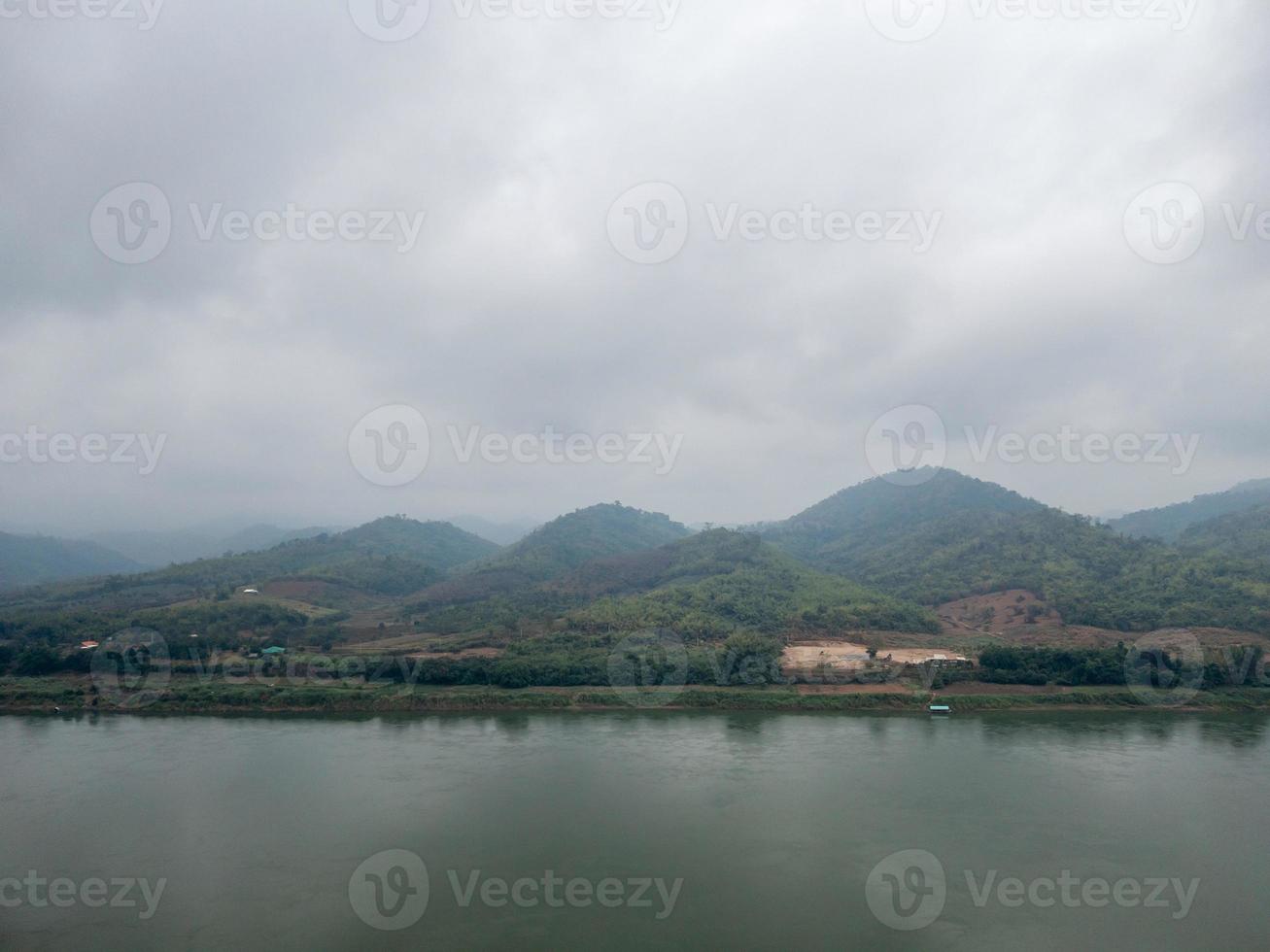 The mountain range is covered by clouds near the large river. photo