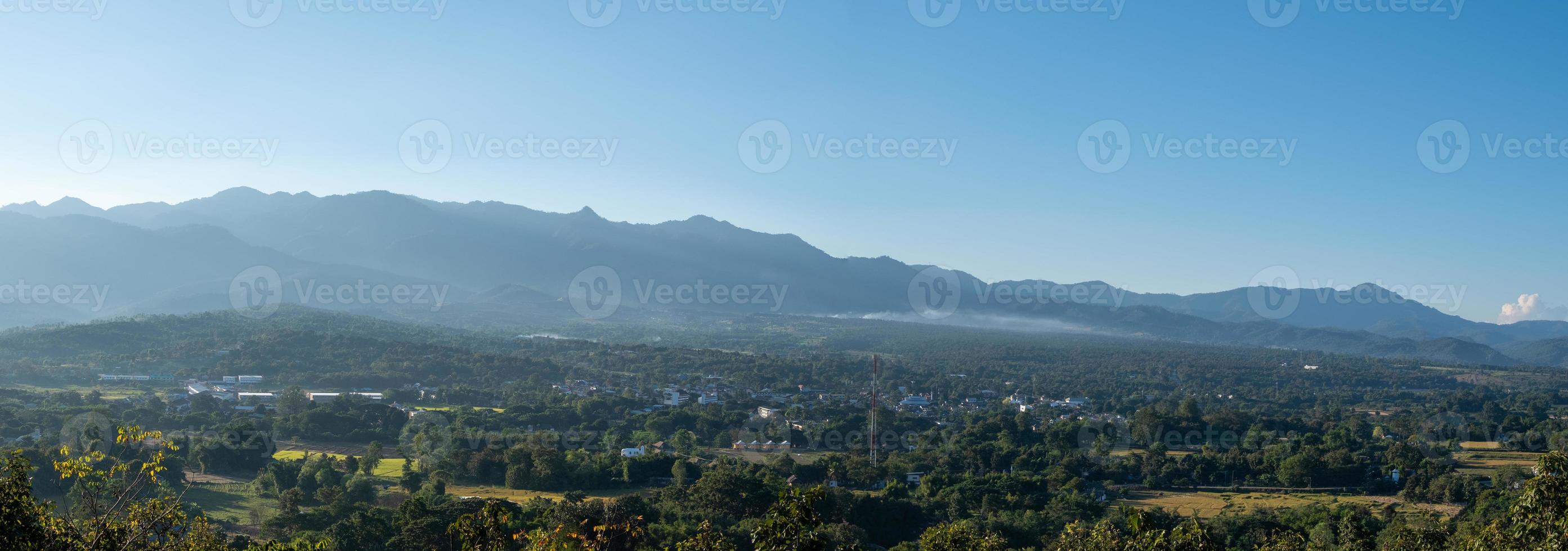 Panoramic view from the viewpoint to the small town located in the plains between the high mountains ranges. photo