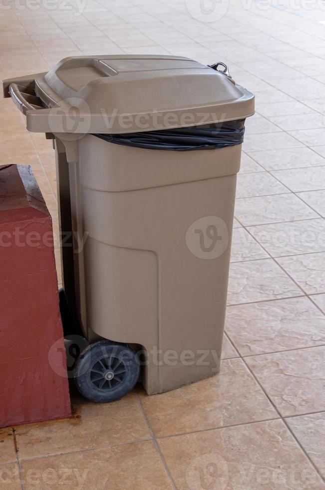 el gran cubo de basura de plástico con mango de metal cerca del poste en la plataforma de la estación de la ciudad. foto