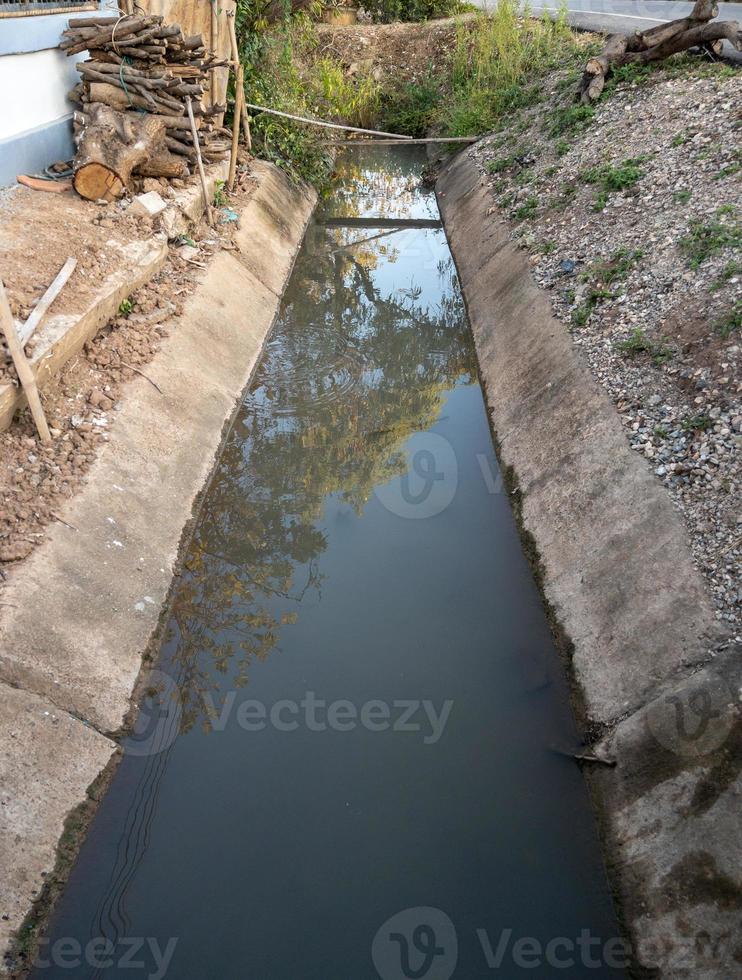 The concrete drainage ditch runs in front of a farmer's house. 9392151