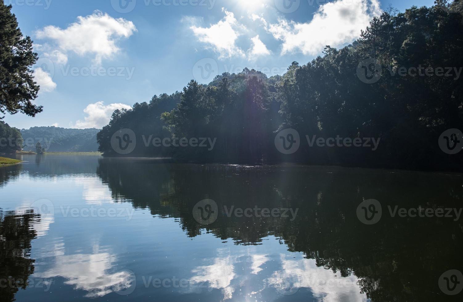 Light beam is lighting the water surface with the smoke in the early morning. photo