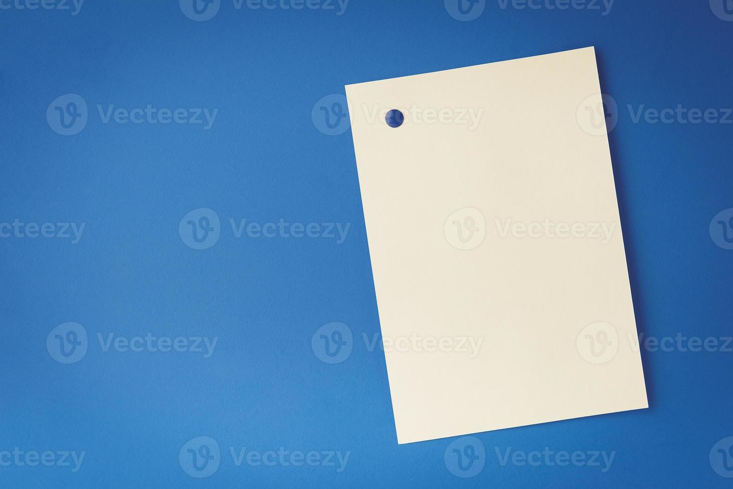 empty white sheet is pinned with a button on blue background photo