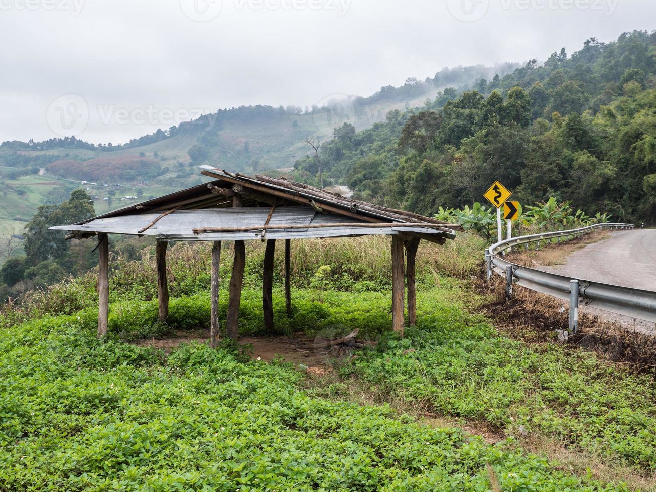 Old wooden shed near the curve asphalt road. photo