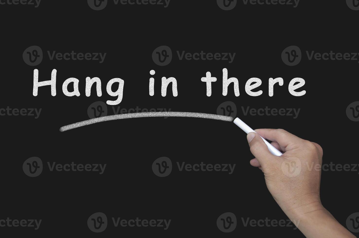 Motivational text written with chalk on blackboard - Hang in there. Motivational concept photo