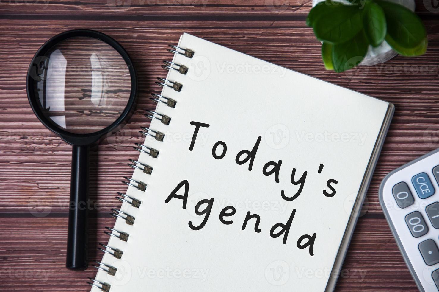 Today's agenda text on notepad. Magnifying glass and calculator background. photo