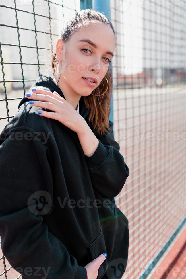 Fashionable stylish woman with collected hair wearing black pullover posing at camera photo