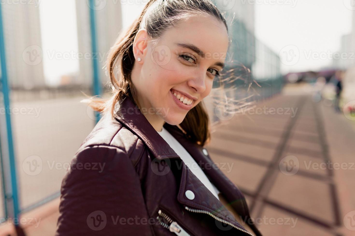 primer plano retrato de ternura mujer con maravillosa sonrisa posando en cámara sobre fondo cuadrado deportivo foto