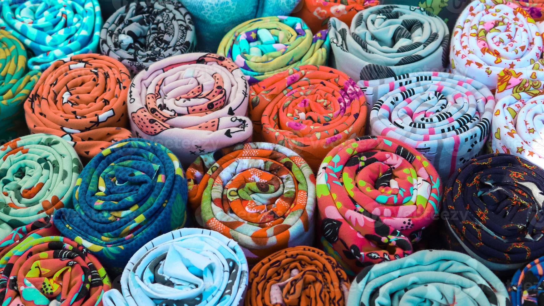 Close up view on rolled samples of cloth and fabrics in different colors found at a fabrics market.. photo