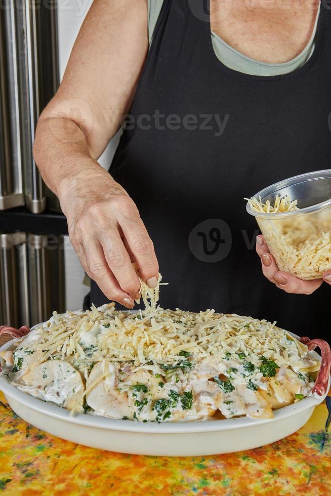 el chef pone queso parmesano en un pescado gratinado con patatas y manzanas. exquisita cocina francesa foto