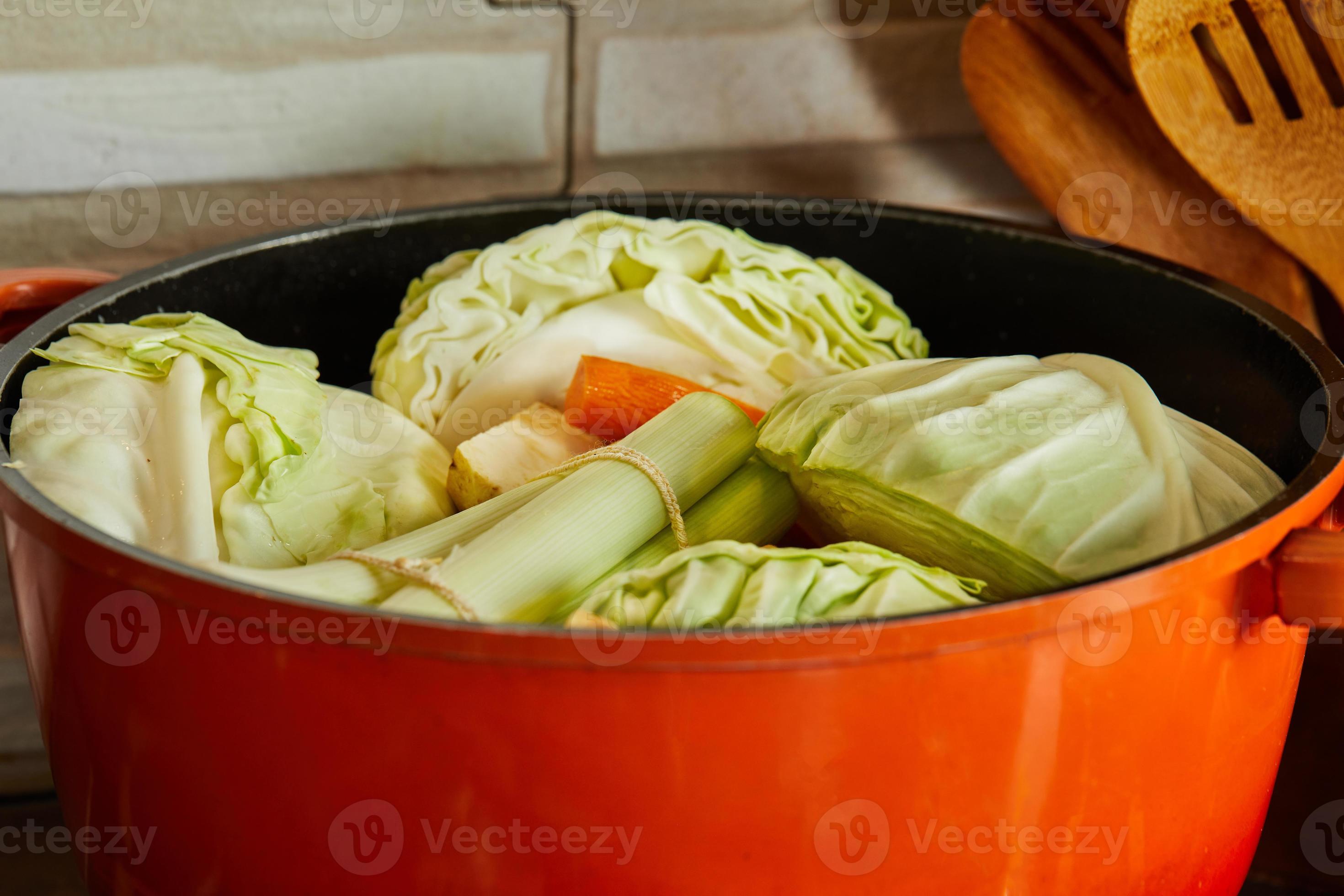 Leek, cabbage, radish, carrots and onions are cooked in pot on gas