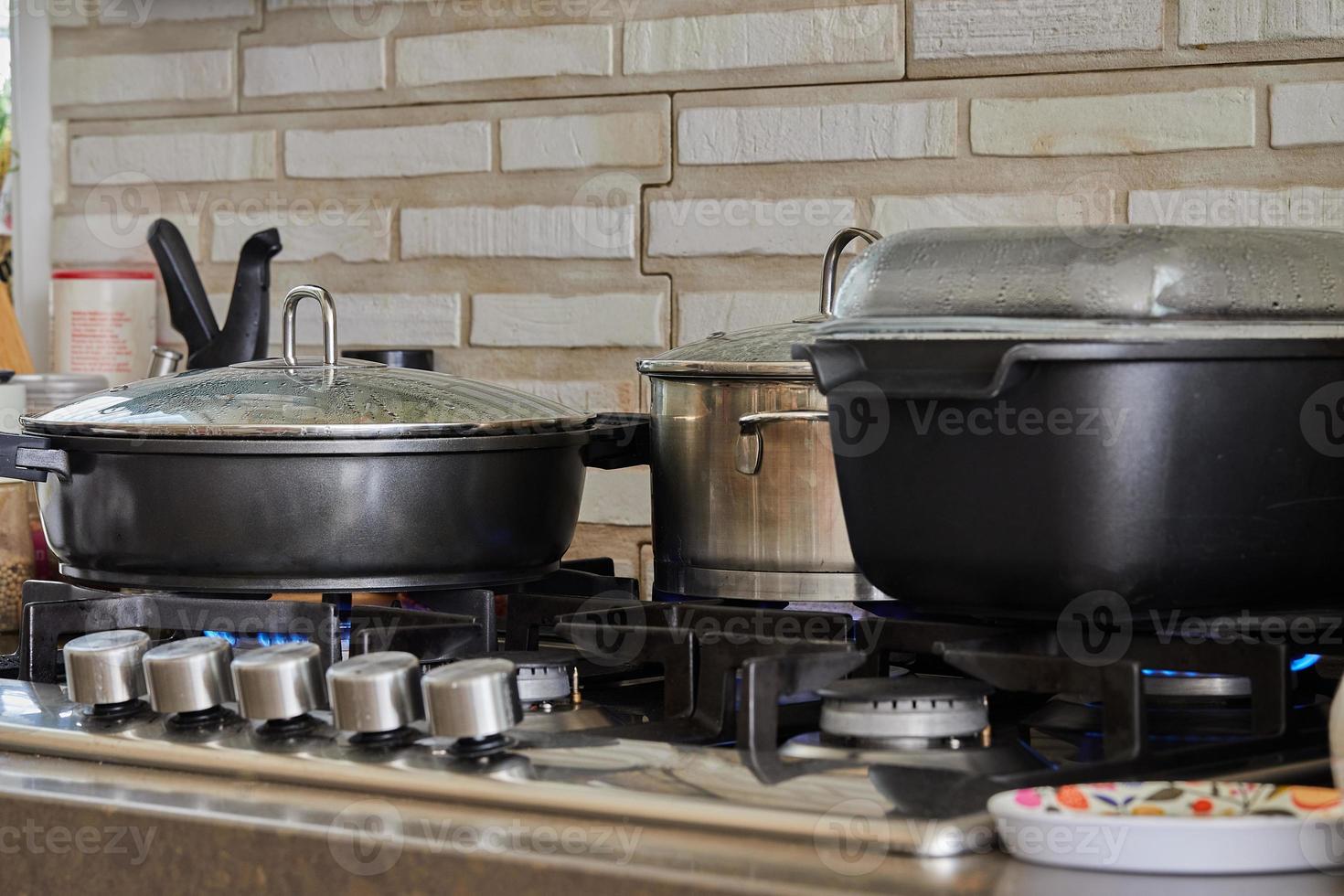 Preparing food in frying pan and casseroles on the gas stove in the kitchen. Home cooking concept photo
