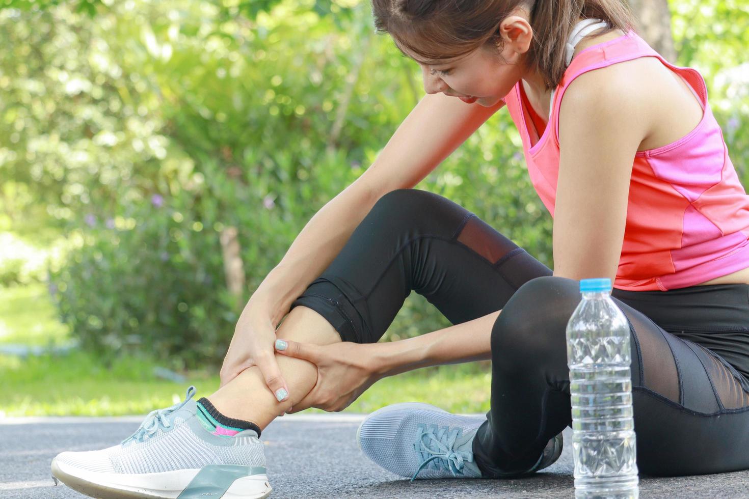 Beautiful woman athlete has ankle pain from jogging in the park. healthy exercise photo