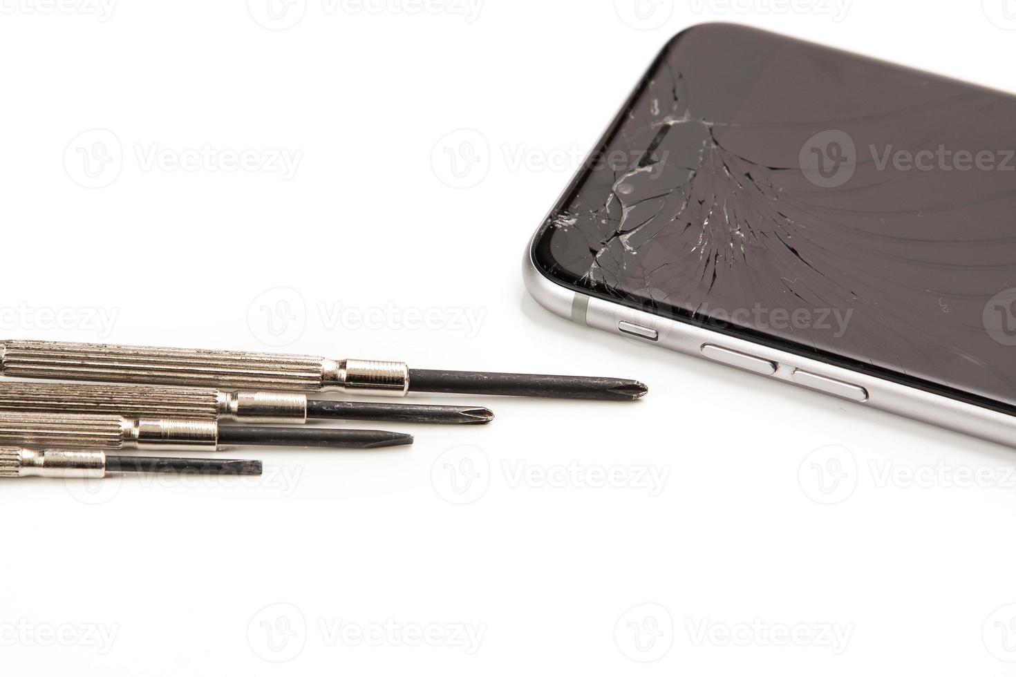 Broken smartphone and small screwdrivers for repair photo