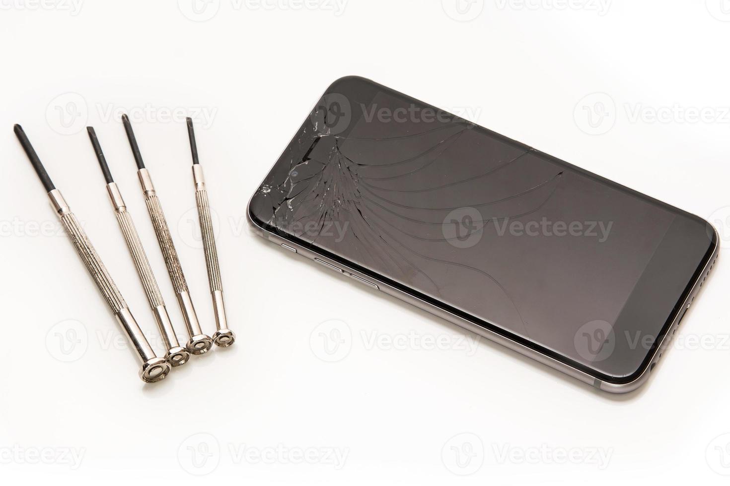 Broken smartphone and small screwdrivers for repair photo