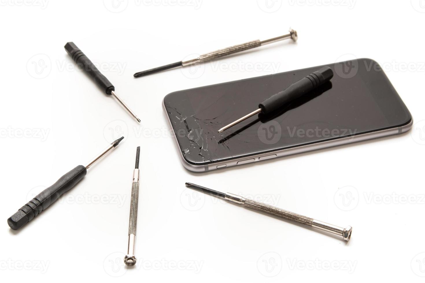 Broken smartphone and small screwdrivers for repair photo