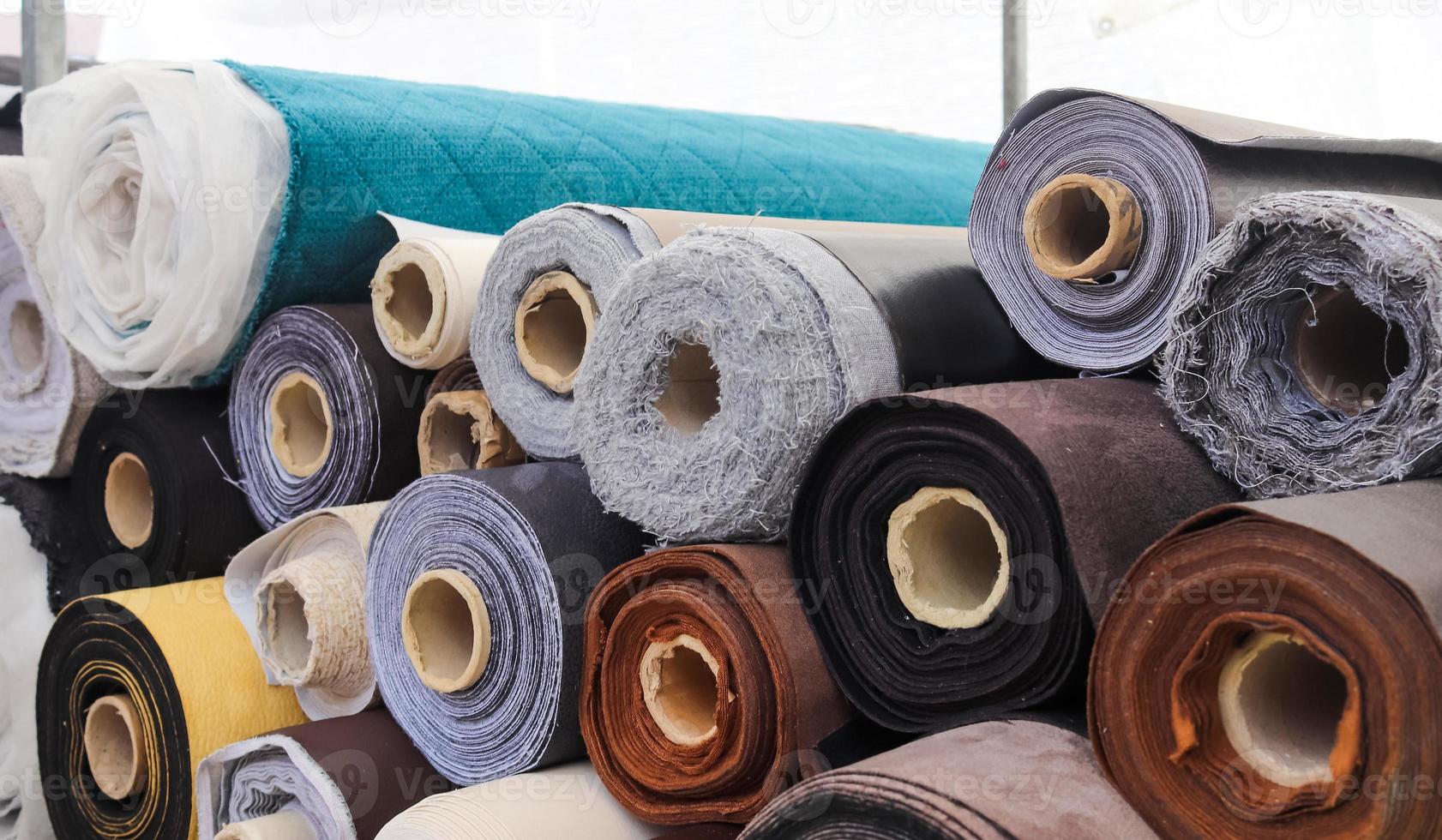 Close up view on rolled samples of cloth and fabrics in different colors found at a fabrics market.. photo