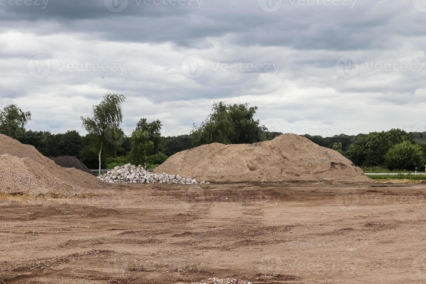 View into a gravel pit with piles of sand and some tire tracks photo