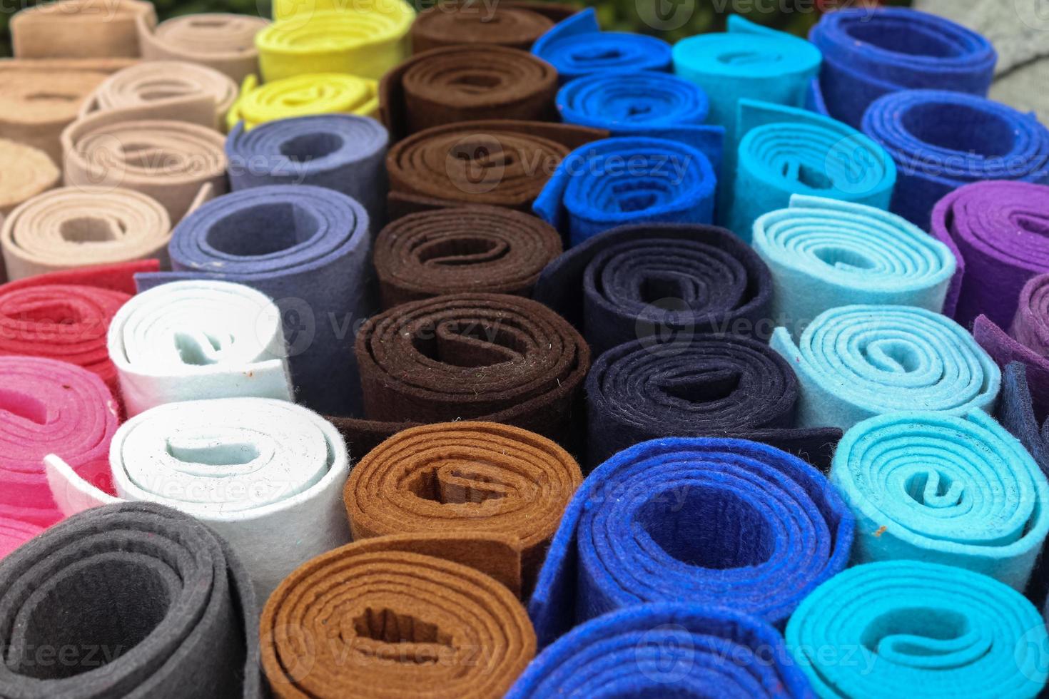 Close up view on rolled samples of cloth and fabrics in different colors found at a fabrics market.. photo