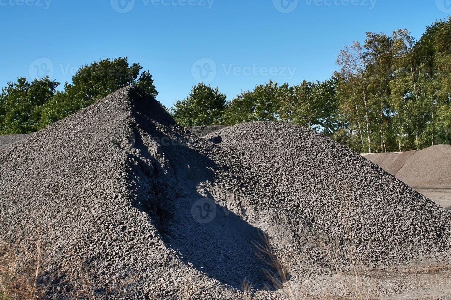 View into a gravel pit with piles of sand and some tire tracks photo