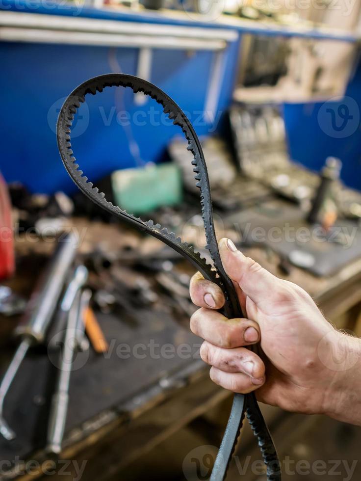 Old worn rubber alternator belt in men's hands. The concept of car maintenance. Copy space photo