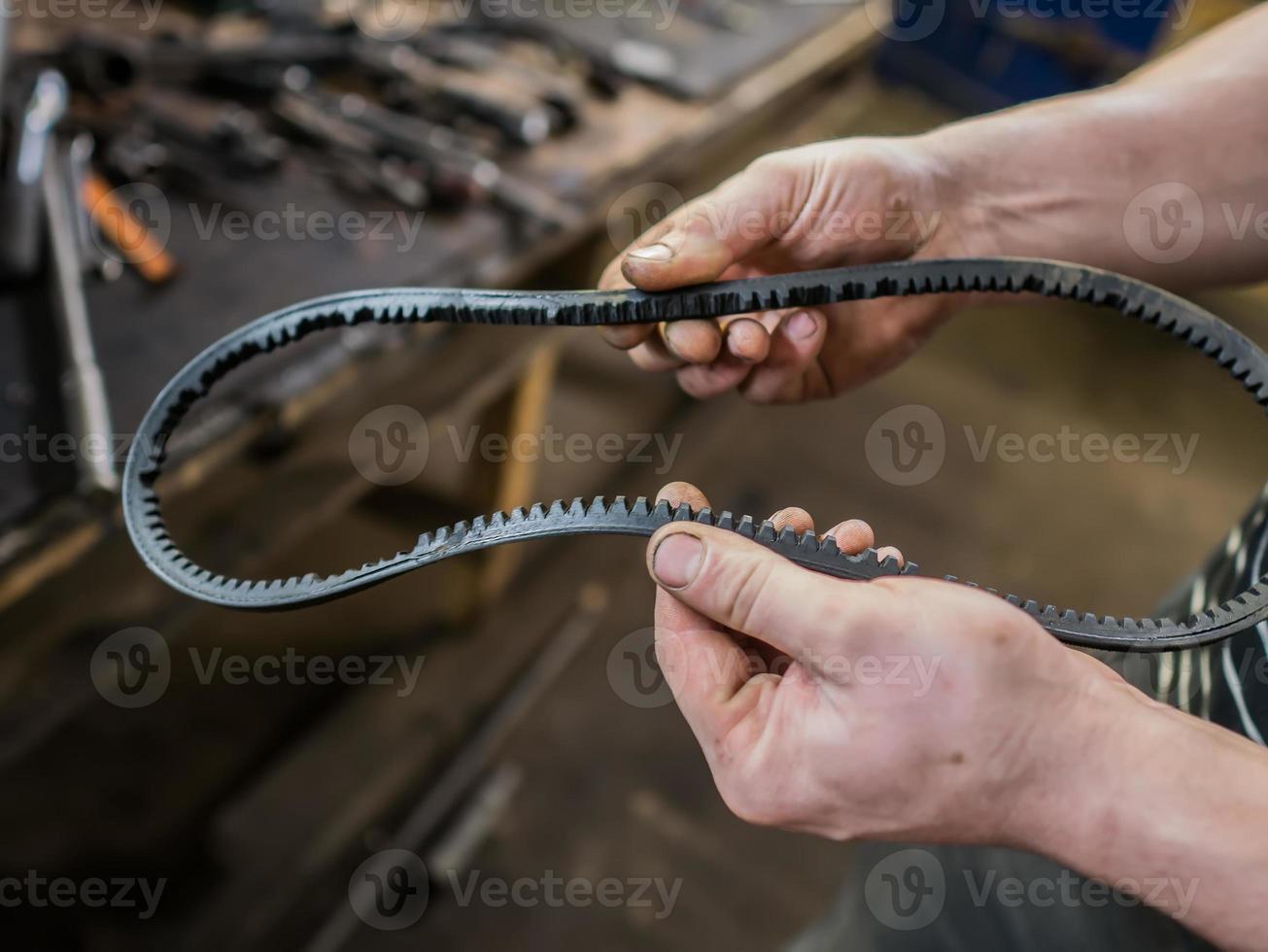 Old worn rubber alternator belt in men's hands. The concept of car maintenance. Copy space. photo