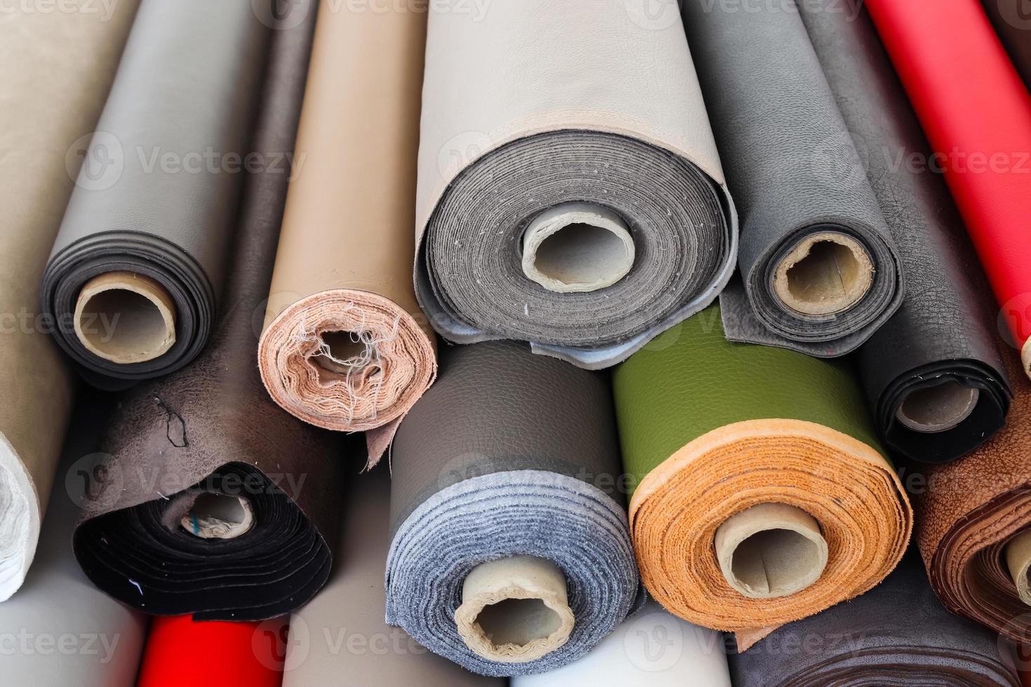 Close up view on rolled samples of cloth and fabrics in different colors found at a fabrics market.. photo