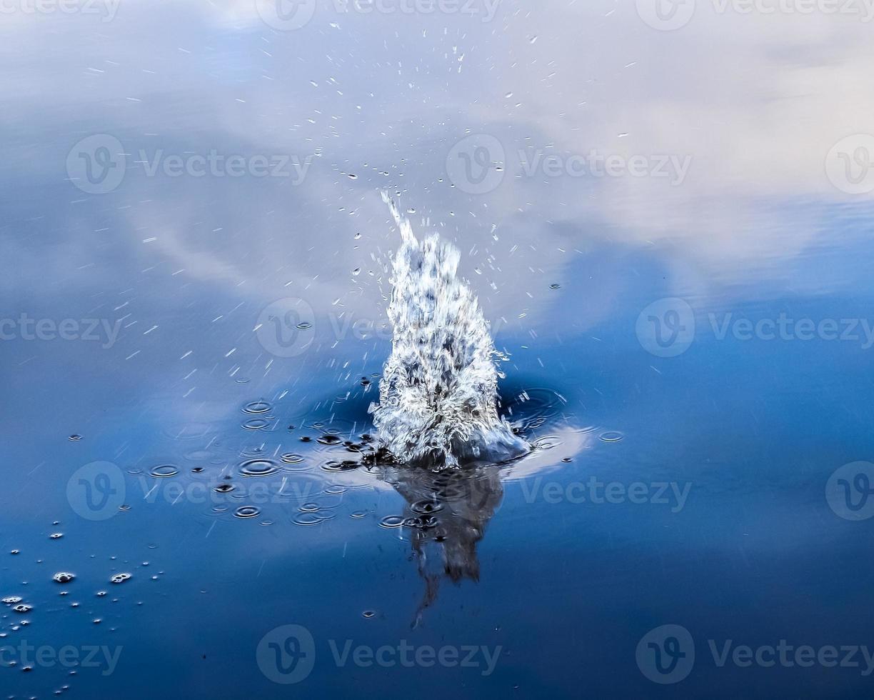 Beautiful water at a lake with splashing water and ripples on the surface with clouds and blue sky reflections photo